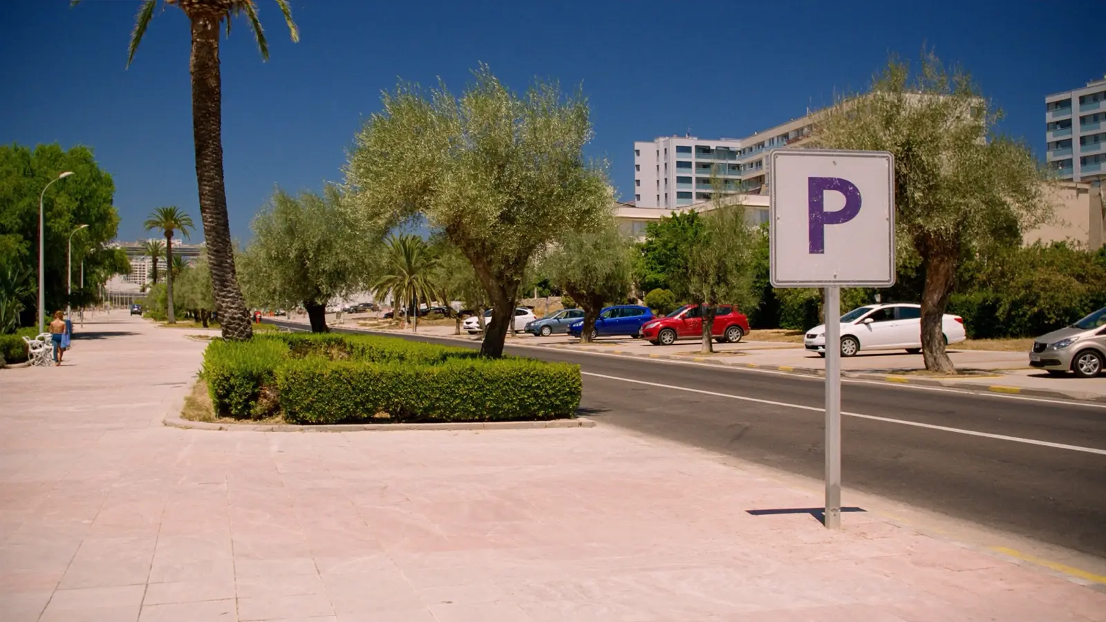 A street in Budva with a purple parking zone sign and cars parked along the kerb