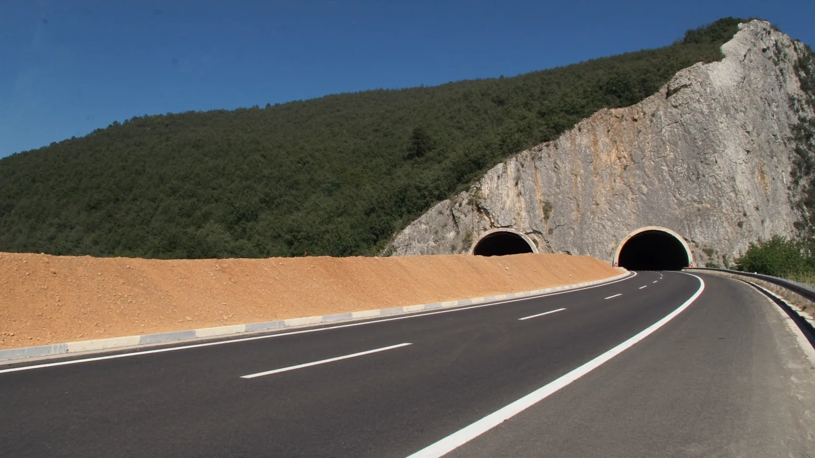 The A1 motorway in Montenegro running toward twin tunnel portals bored into a limestone crag
